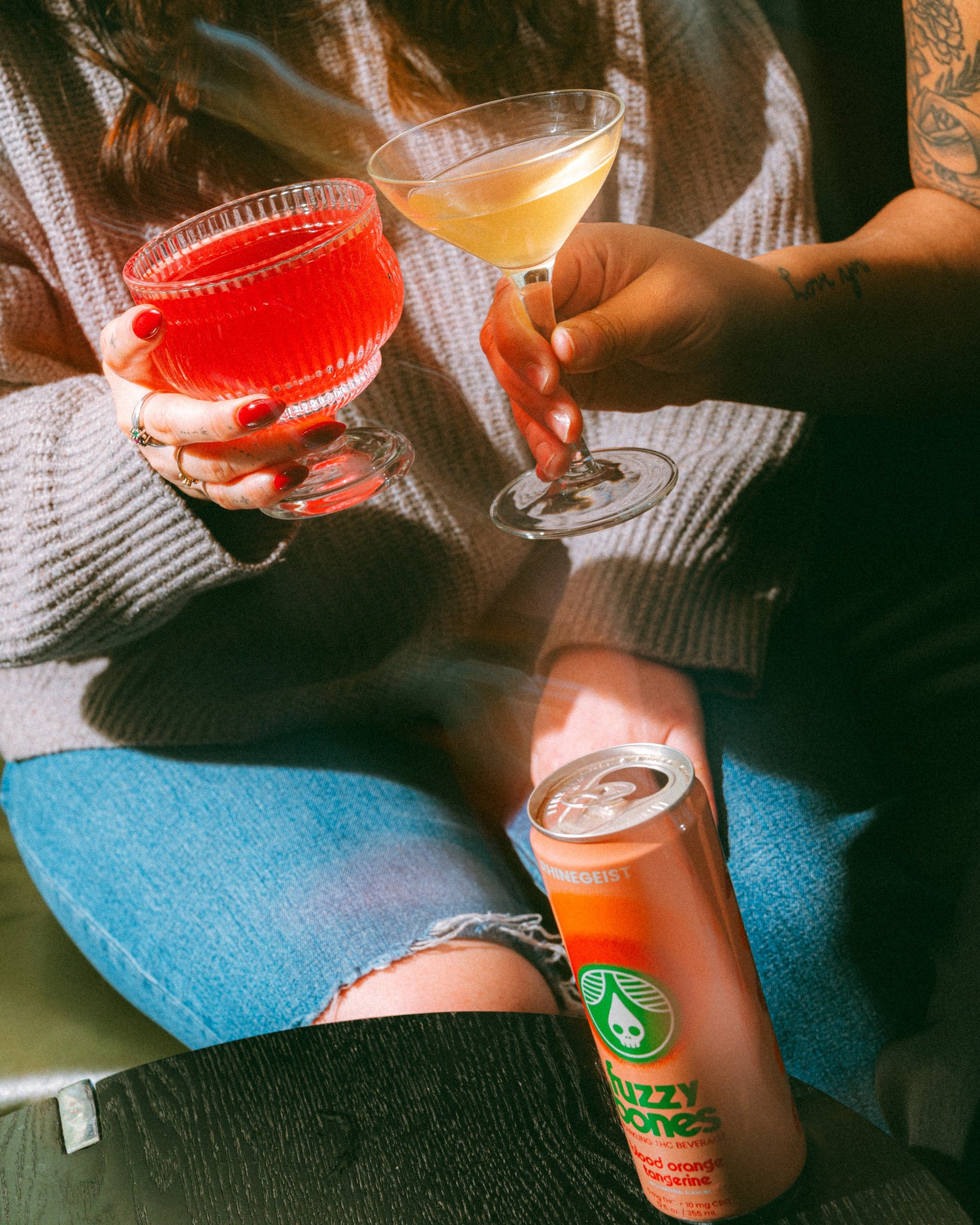 Two people holding drinks with a can of Fizzy Bones in the foreground.