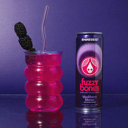 Fuzzy Bones blackberry cocktail with a glass and straw on a purple background